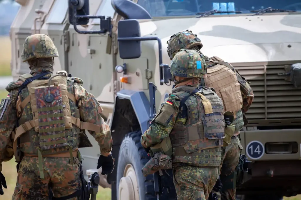 Bundeswehr Soldaten in Tarnausrüstung von hinten, Panzer im Hintergrund