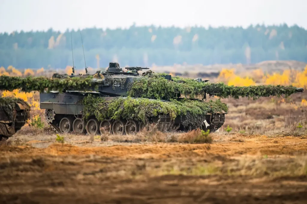 Bundeswehr-Kampfpanzer Leopard mit Tarnung aus Tannenzweigen im Gelände